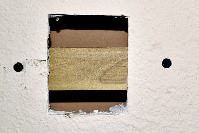 Using a piece of wood as a support for drywall patch