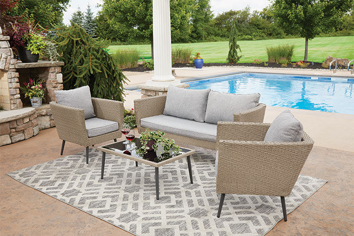 Tan patio furniture set up outside next to a pool 