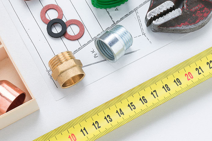 Banner image of plumbing materials including copper elbow joints, washers, and couplers with pipe wrench and tape measure