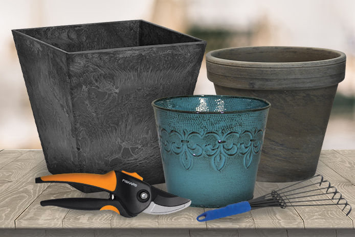 A lifestyle image of three garden planters with a pair of fiskar pruners and a hand garden rake on a wooden table