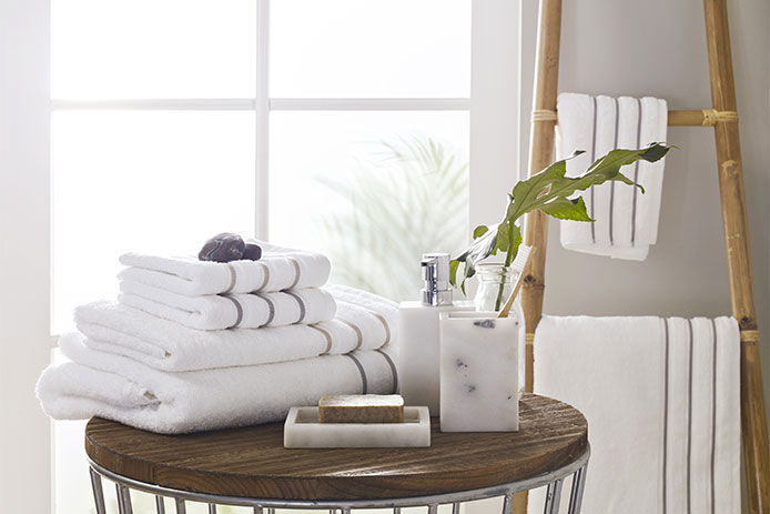 Some clean folded bathroom towels on a small table in front of a window