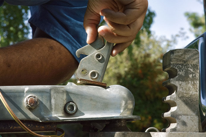 Close-Up Shot of a Hispanic Man's Hands Closing the Latch on the Trailer Coupler on a Sunny Day