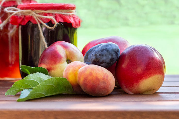 Close-up image of peaches with a couple canned jars of fruit in the background
