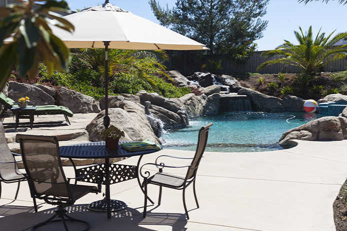 An umbrell and two chairs next to a pool