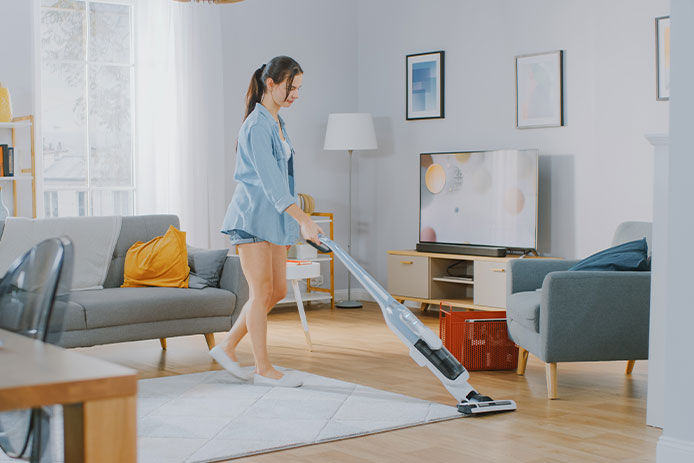 Woman sweeping in her living room with a vacuum