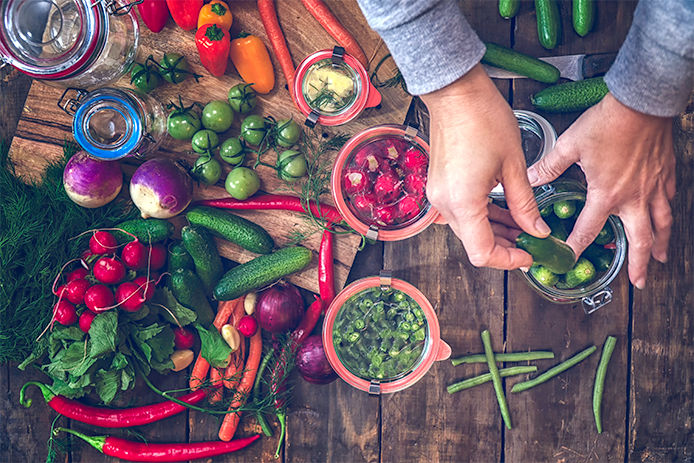 Preserving organic vegetables in jars like carrots, cucumbers, tomatoes, chilis, paprika and radishes.