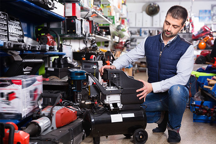 Man taking a look at an air compressor in the store before purchasing
