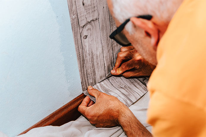 Wallpapering. A man glues gray vinyl wallpaper on a non-woven backing. Renovation of the room. Hang wallpaper. Home repairs