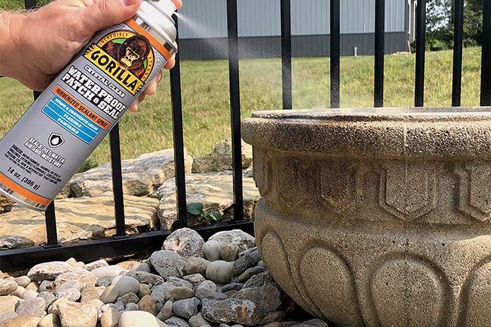 A person using Gorilla Waterproof Patch and Seal areosal can to seal up a stone planter 