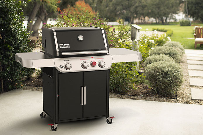 Lifestyle imgae of a Weber Genesis gas grill sitting on a stone patio 