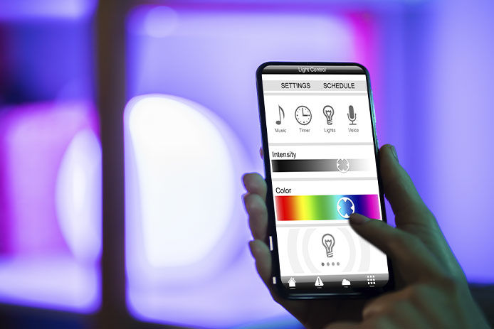Person holding their phone with smart lighting settings to control smart lights