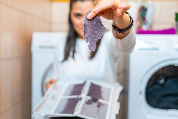 Woman holding out a piece of lint from the lint trap of a dryer
