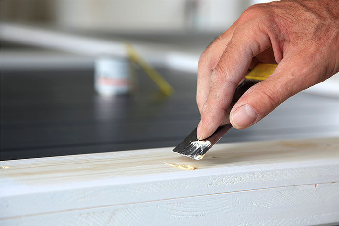 Using wood putty to fill a hole in a door