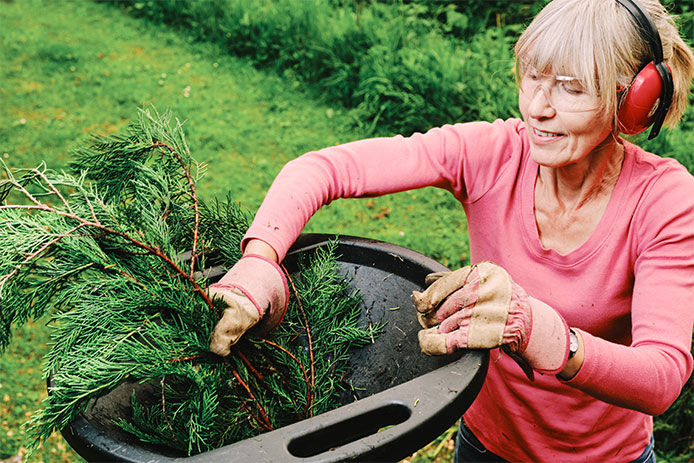 Woman wearing ear and eye protection while chopping up a Christmas tree