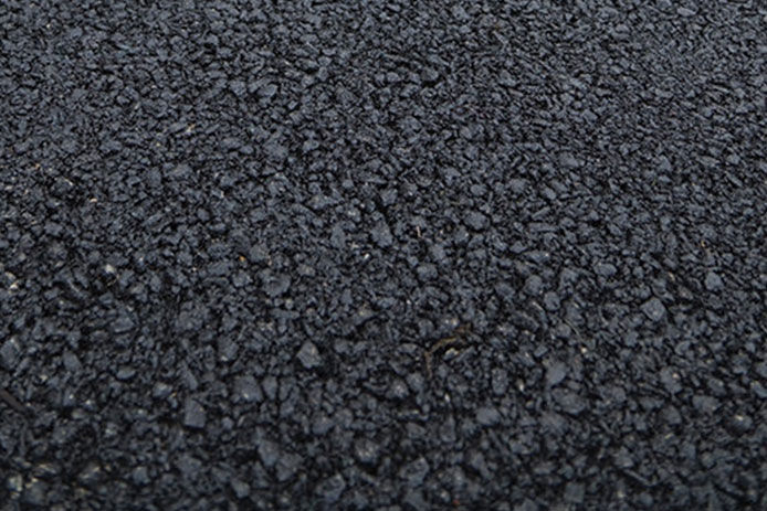 A closeup of black asphalt, showing little rocks embedded in a sticky black surface.