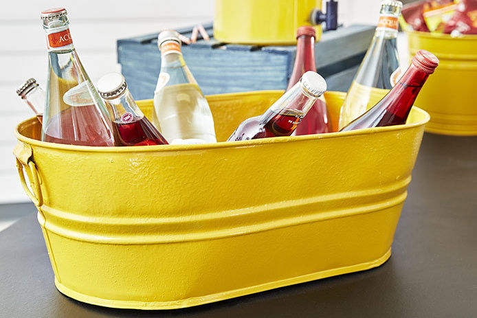 Small bright yellow metal cooler with ice and sodas