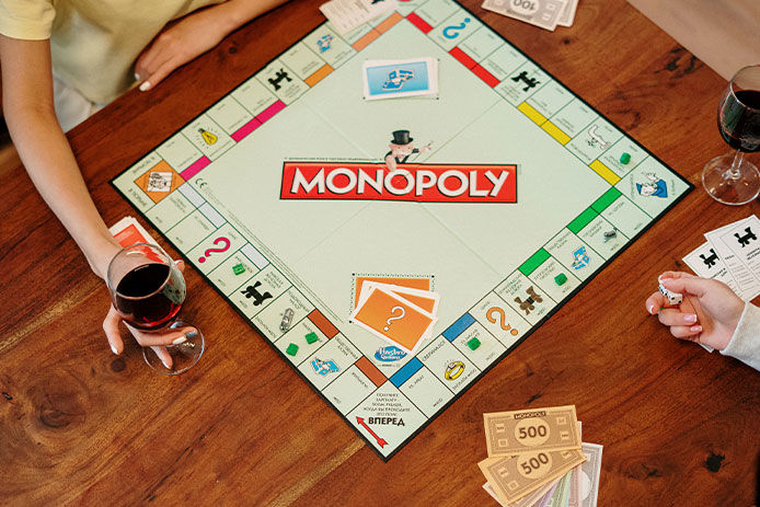 Overhead view of a family playing Monopoly at the dining table