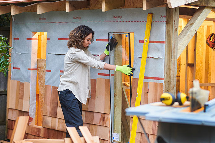 Woman setting the glass wndowin place for her shed