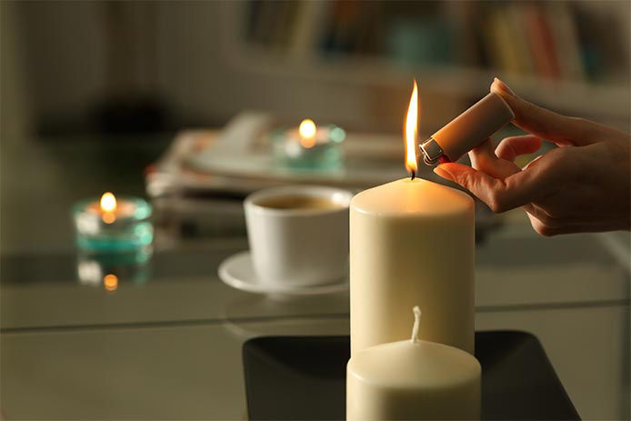 Person lighting a candle with a lighter in a dimmly lit room