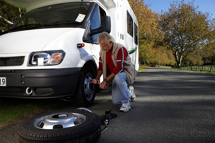 A man changing a tire on an RV