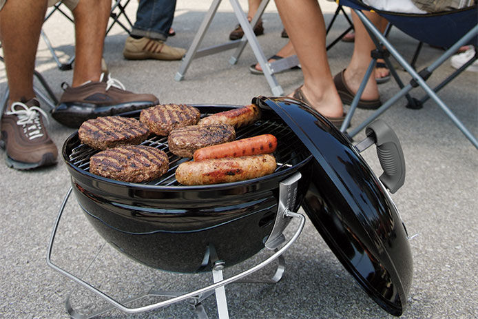 Burgers and brats on a small tailgating chargoal grill