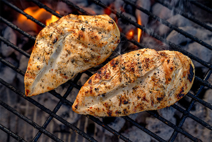 Seasoned chicken on charcoal grill grates cooking