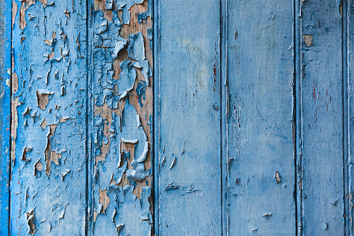 Blue paint chipping off of a wood panel