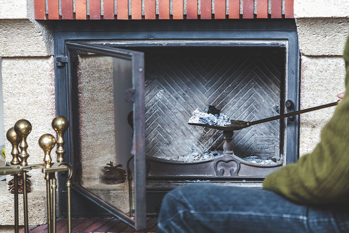 A man cleans the fireplace. Taken out of the fire a long-handled shovel with ash