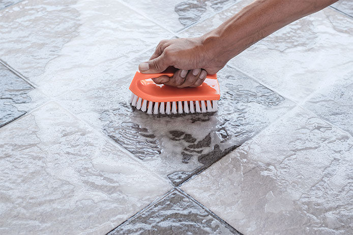 Scrubbing tile floor with an orange scrubber brush