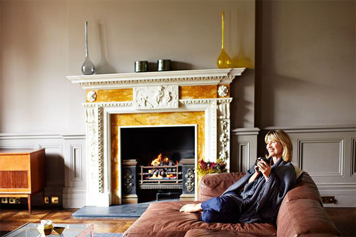 Woman sitting on a couch enjoying a fire