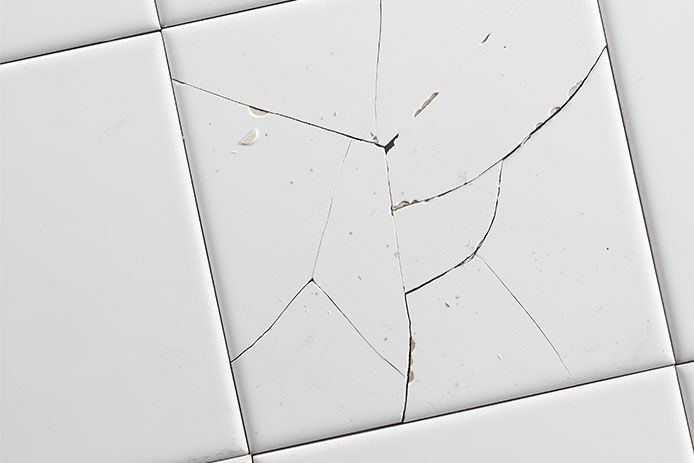 Cracked broken white tile, close-up