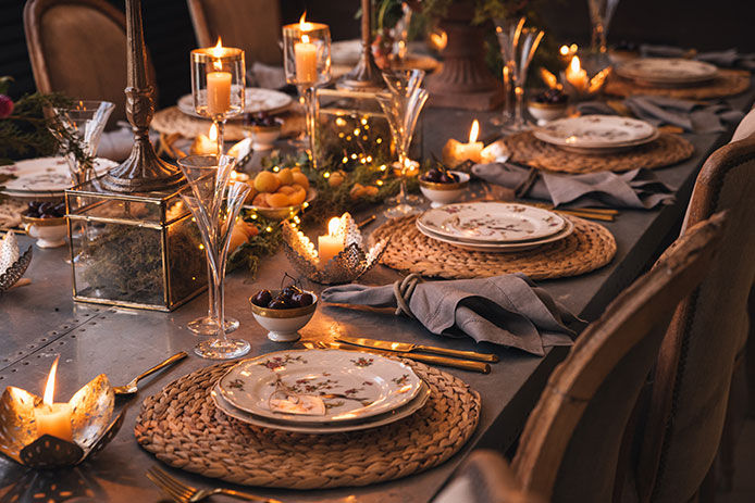 Dimmly lit dining room with dinning table set for dinner with candles lit