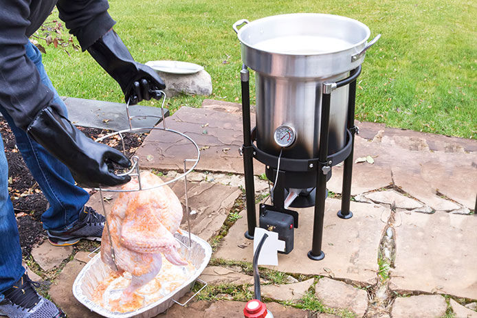 Person prepping turkey to put in deep fryer outside