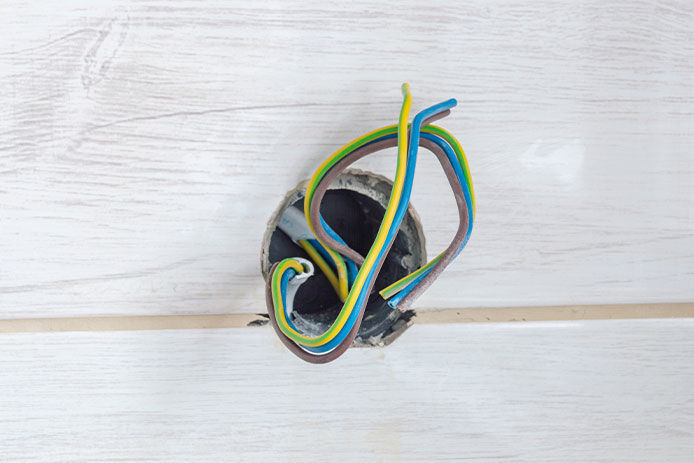 A wooden wall with electrical wires coming out 