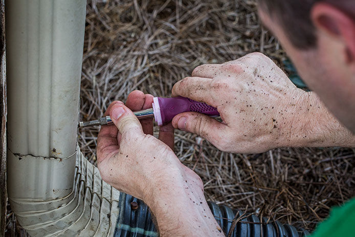 A man adding a downspout extension