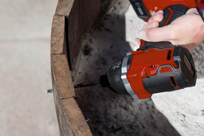 A person drilling holes in a planter with a drill