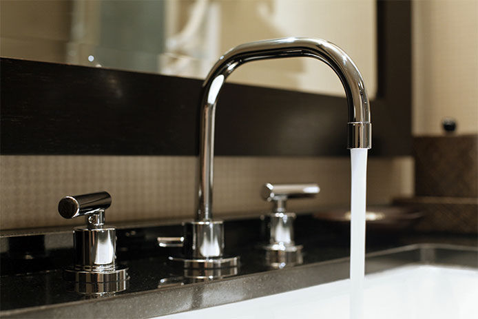 a silver metal faucet running in the sink to help keep the pipes from freezing