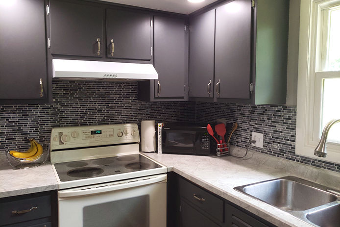 A view of a kitchen with white countertops, stainless steel sink, white appliances and home decor on the counters as accent pieces