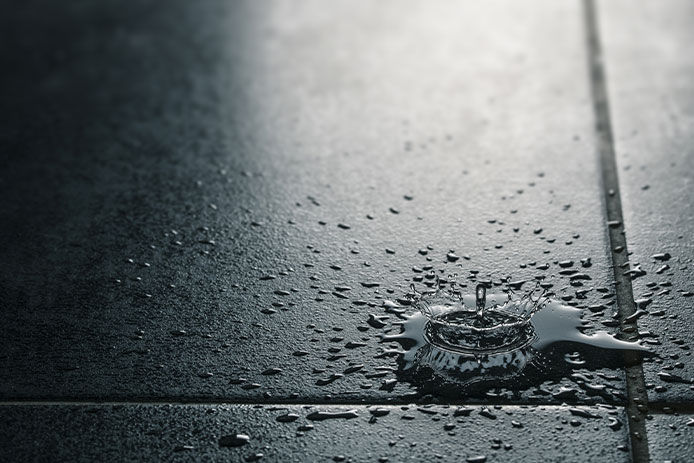 a close up image of dark tiled floors with a splash of water on it 