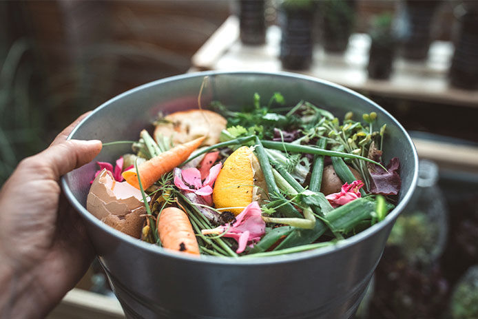 Woman holding a bowl of scraps from the kitchen