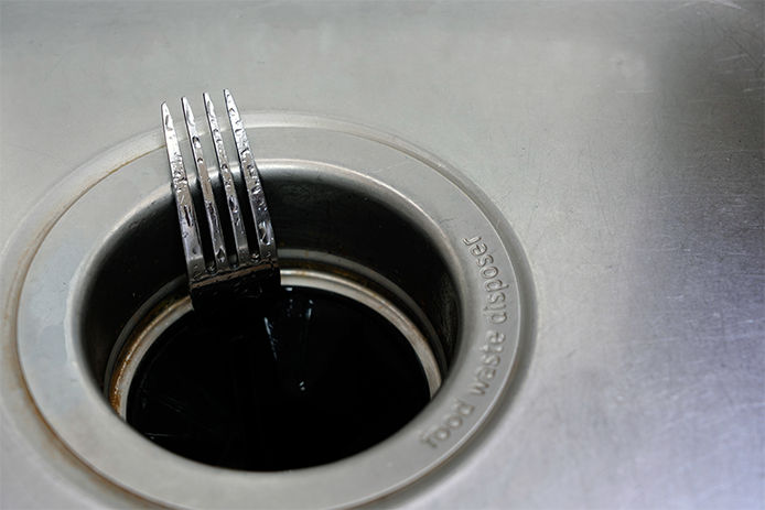 A fork sticking half way out of sink drain