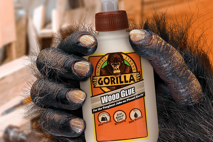 A hairy gorilla hand holding a bottle of Gorilla Wood Glue