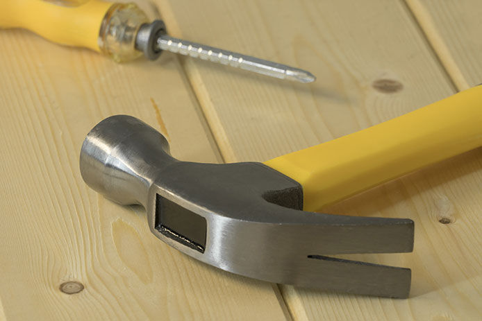 A hammer and screwdriver on a wooden surface