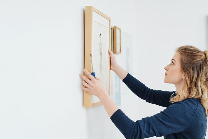 Add personal touches to your mud room like this woman is by hanging up pictures on the wall 