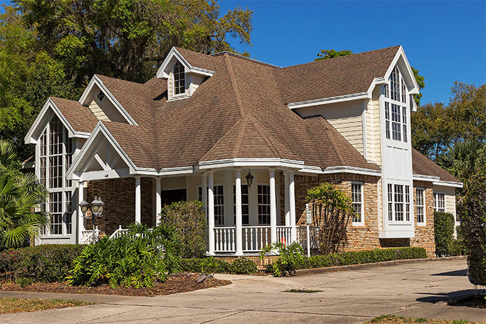 A traditional style house with brown shingles and a white enclosed picket porch