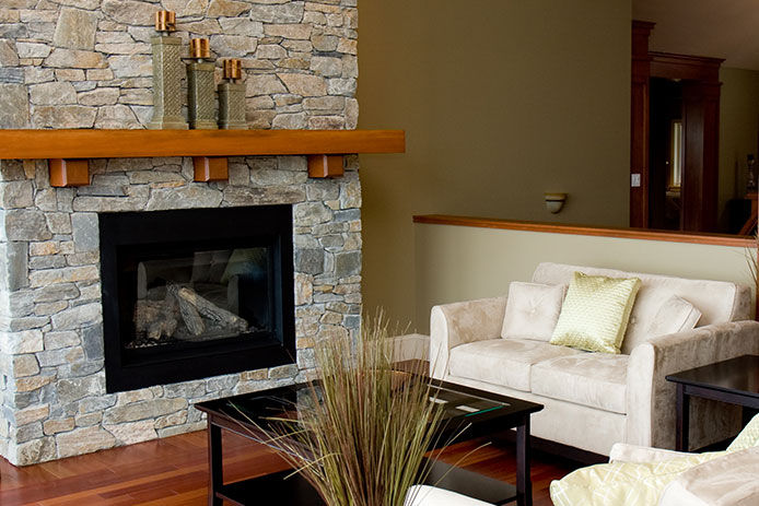 A stone fireplace and beautiful hardwood floors highlight the living room of a new luxury home.