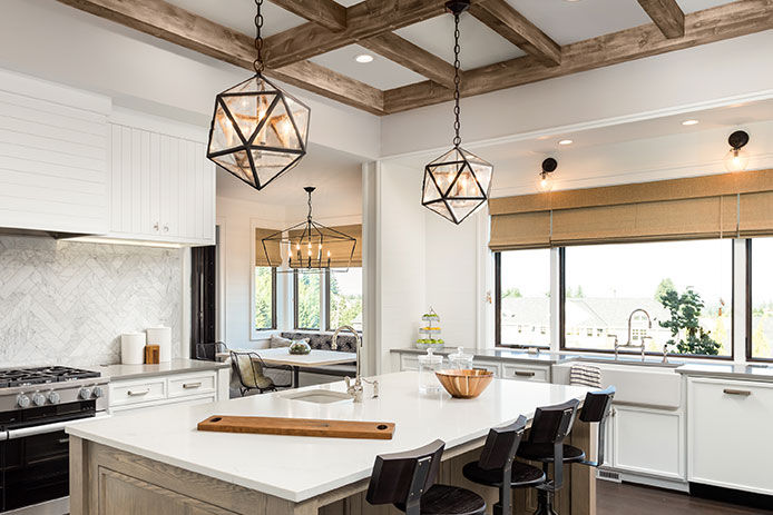 Kitchen Interior with Island, Sink, Cabinets, and Hardwood Floors in New Luxury Home. Includes elegant pendant light fixtures and wood beam ceiling