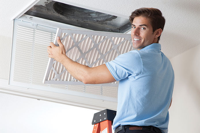 A young man installing an air filter in residential home