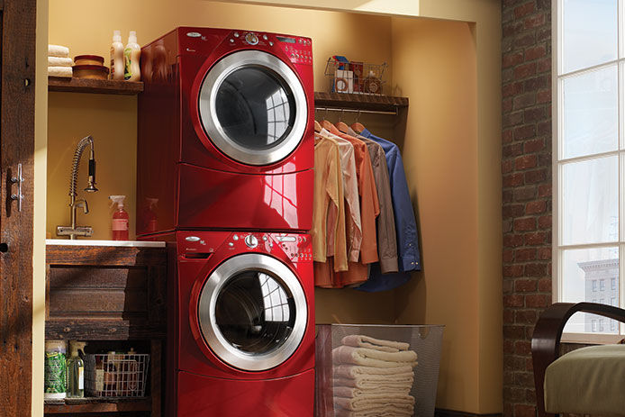 Two red stackable washer and dryers in a closet