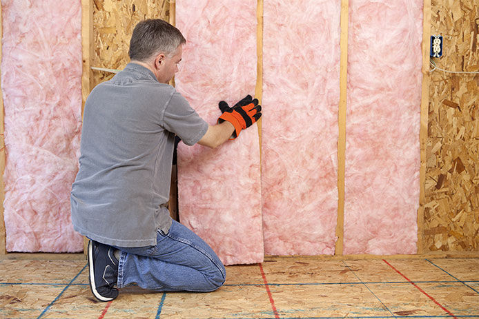 Man installing pink insullation while wearing work gloves